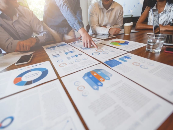 A group of people commenting on the presentation posters with data displayed on a table.