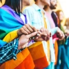 Picture of people holding hands wearing a rainbow flag