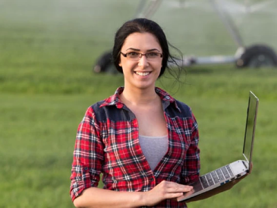 student in a crop field with a laptop