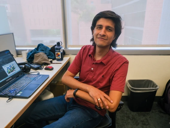 Christian Ayala poses for a photo at his desk in the Tfaily Lab at UArizona campus