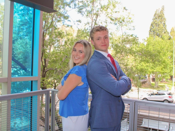 Young male and female college students posing back to back at McClelland Park