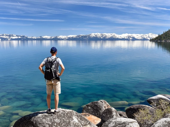 A photo of a person looking out over Lake Tahoe with mountains on the horizon