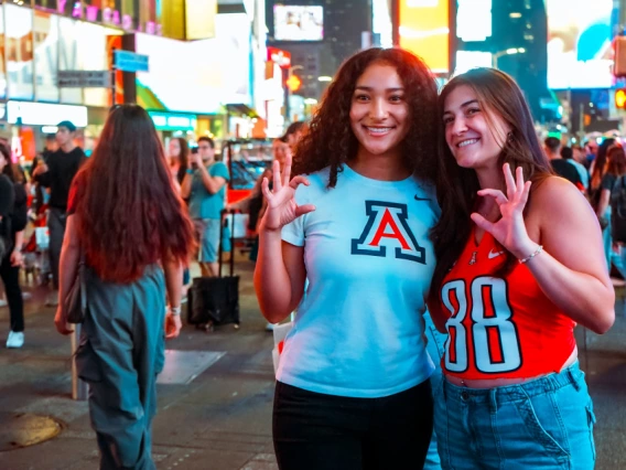 UofA students posing with Wildcat hand sign.