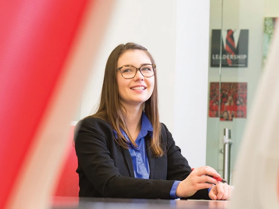 Student in professional attire sitting in a boardroom.