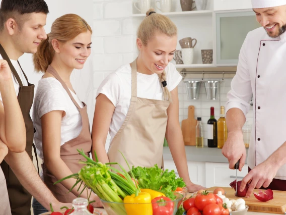 Students and a chef cutting vegetables.