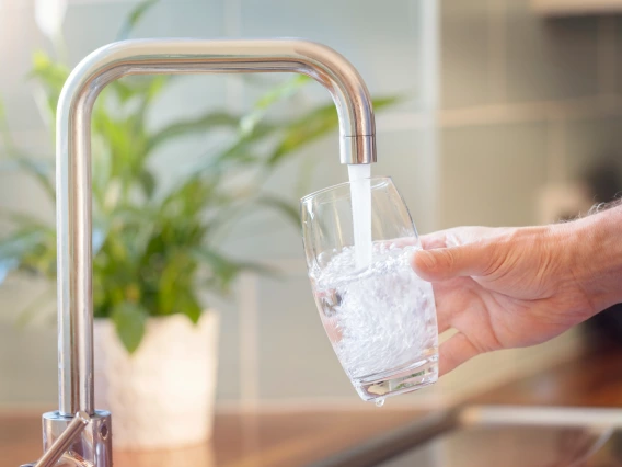 A person fills a drinking glass from the kitchen tap