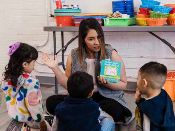 A teacher reads a board book to a group of young children