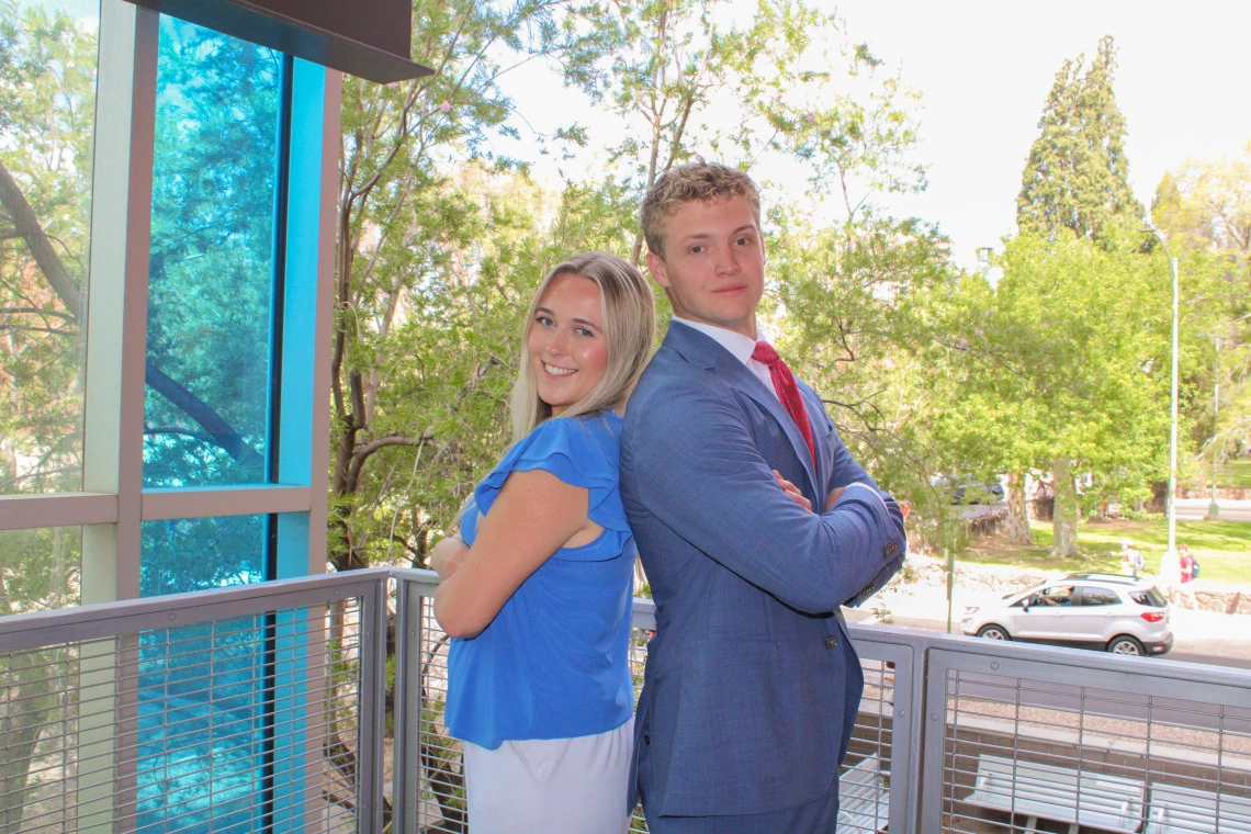 Young male and female college students posing back to back at McClelland Park