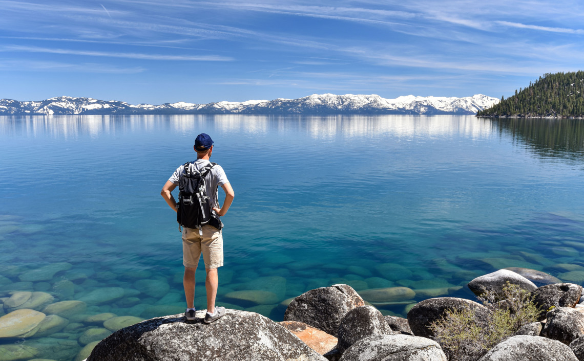 A photo of a person looking out over Lake Tahoe with mountains on the horizon