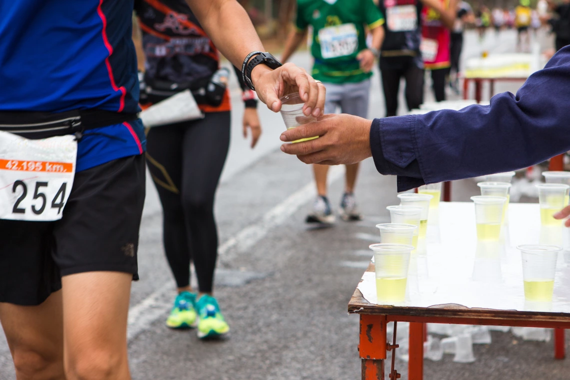 Volunteer hands a runner a cup of sports drink during a race