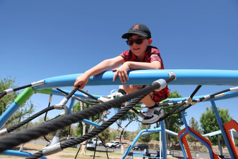 A young boy climbs on a playground jungle gym