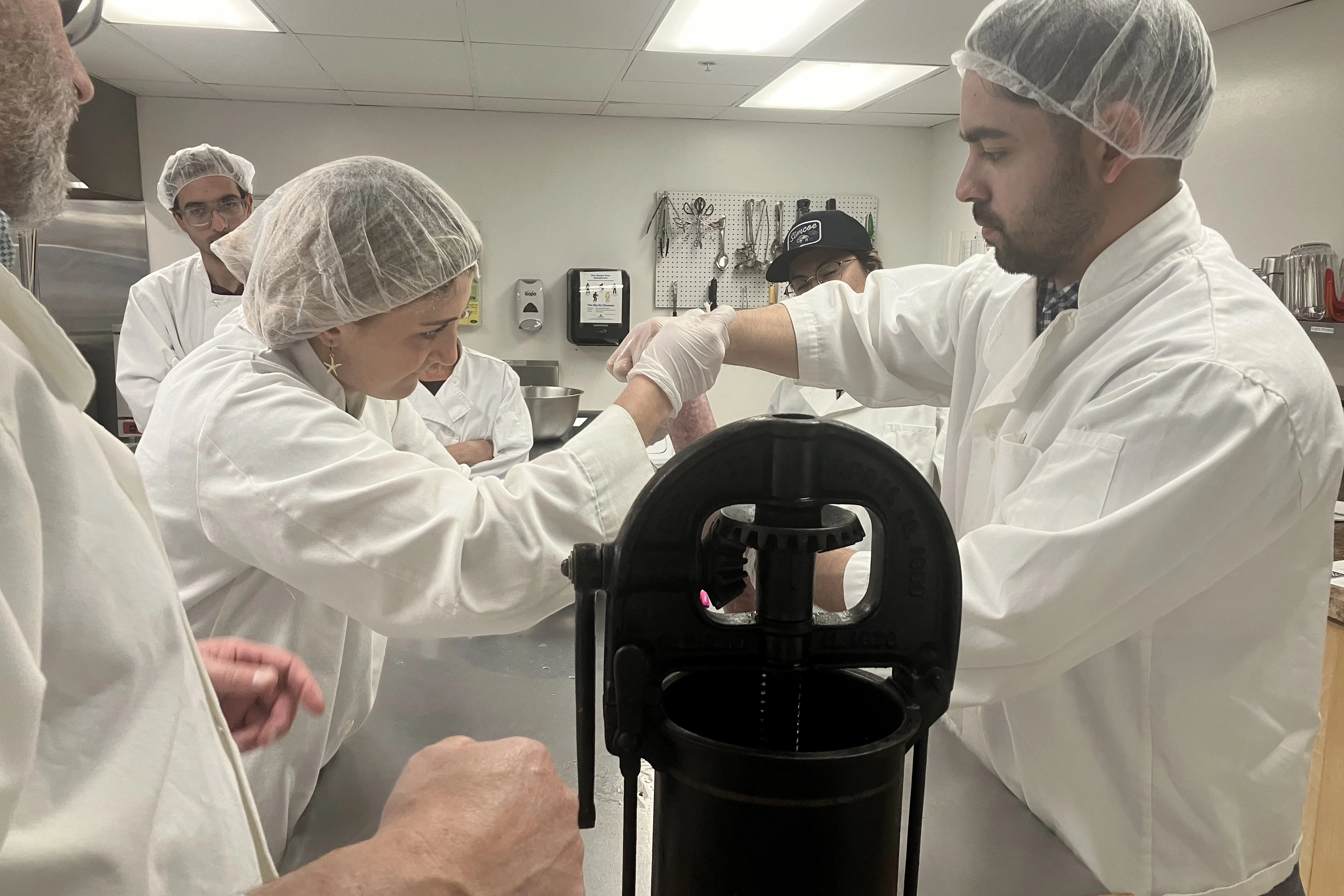 Students working in a sausage stuffing kitchen.