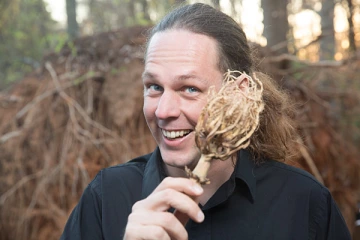 A headshot of Alexander Bucksch holding a root structure