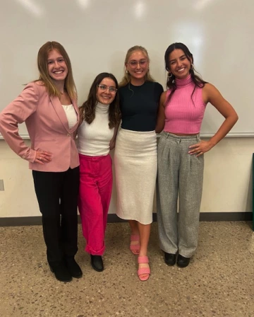Four female college students posing in of a whiteboard