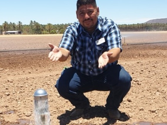 Extension Agent Hector Munoz points to an in-field sprinkler head