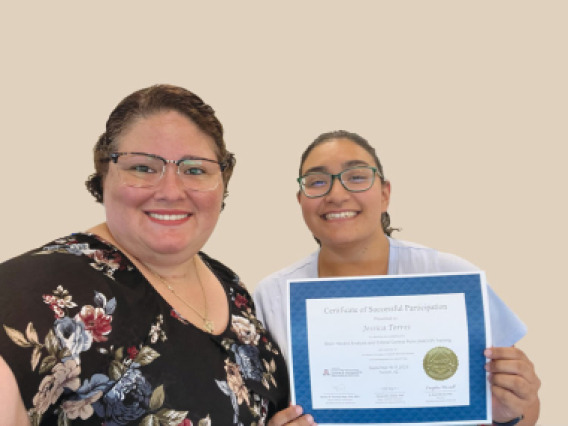 Margie Sanchez-Vega stands next to ACBS student Jessica Torres, who holds up a certificate