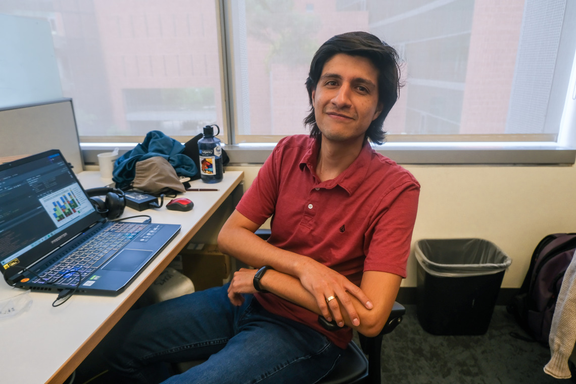 Christian Ayala poses for a photo at his desk in the Tfaily Lab at UArizona campus